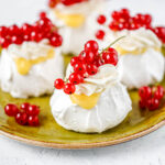 White meringue pastry decorated with fresh berries on the green plate.