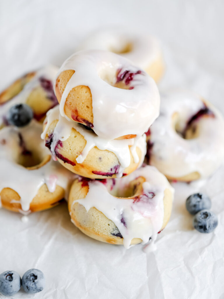 Stock of baked blueberry donuts with the glaze. 