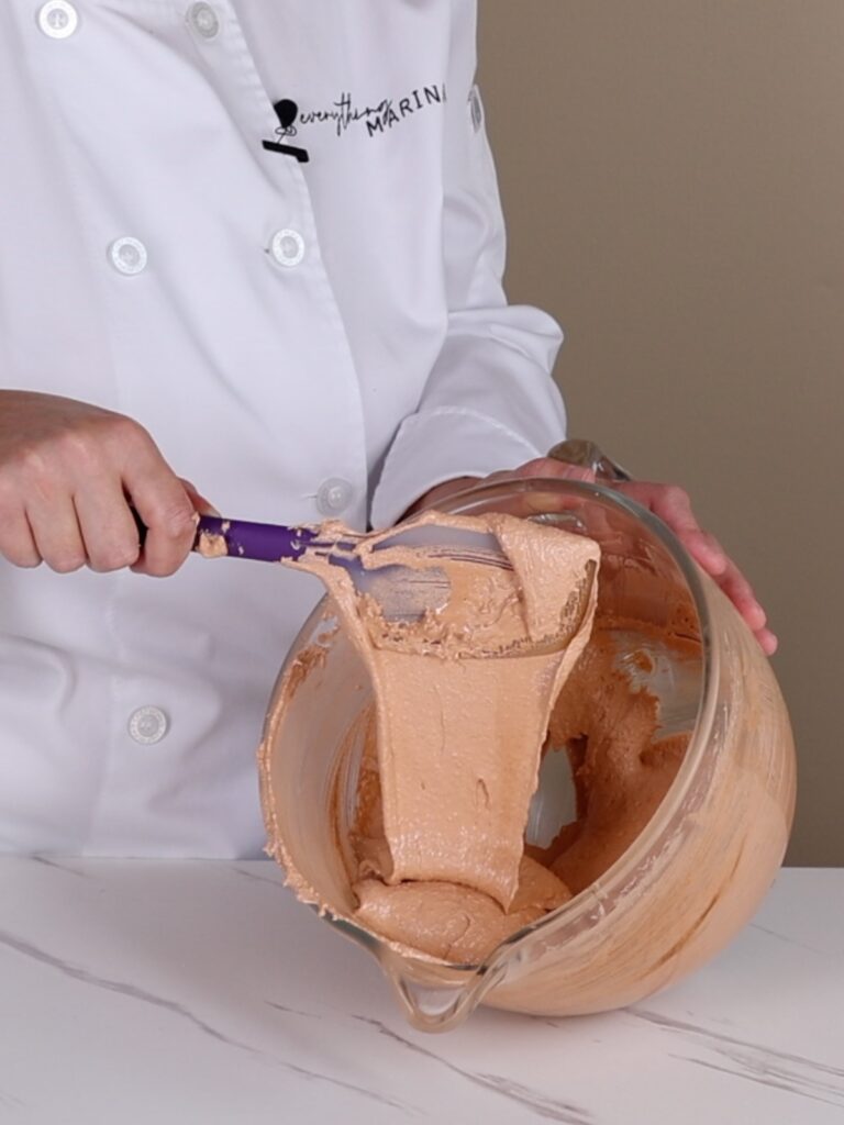 Macaronage in the bowl flows from the spatula.