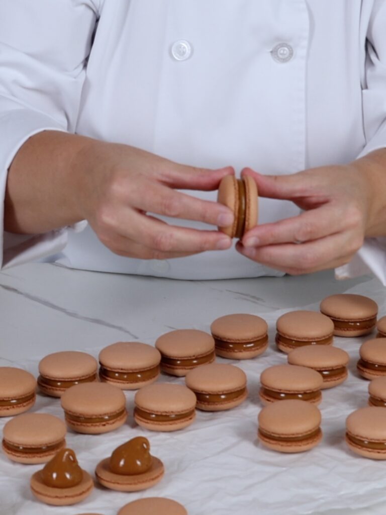 Assembling salted caramel macarons.