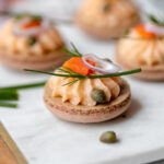 Cream cheese filling piped on one macaron shell and topped with smoked salmon.