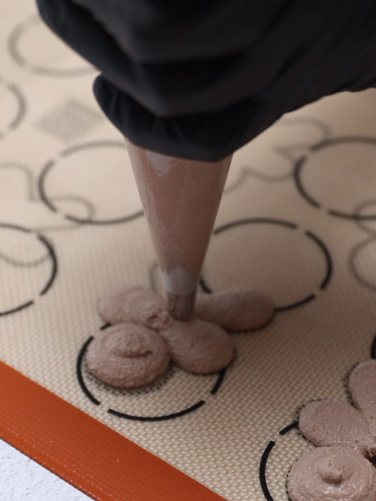 Piping gingerbread man macarons. 