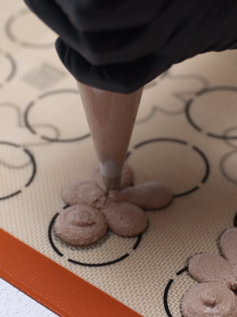 Piping gingerbread man macarons.