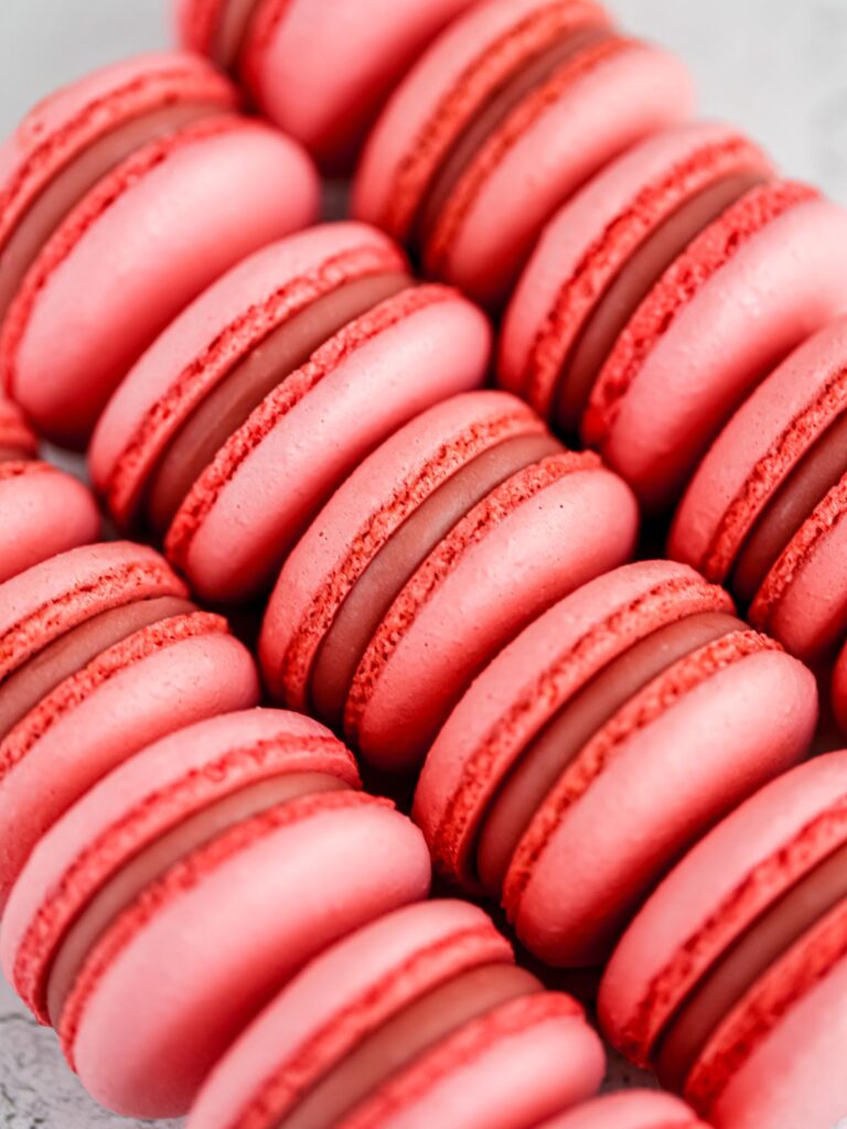 Pink macarons are placed on the table. 