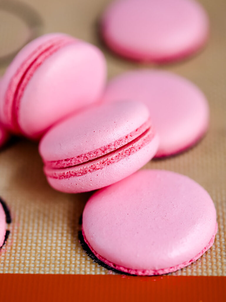 Pink macaron shells on the baking mat. 