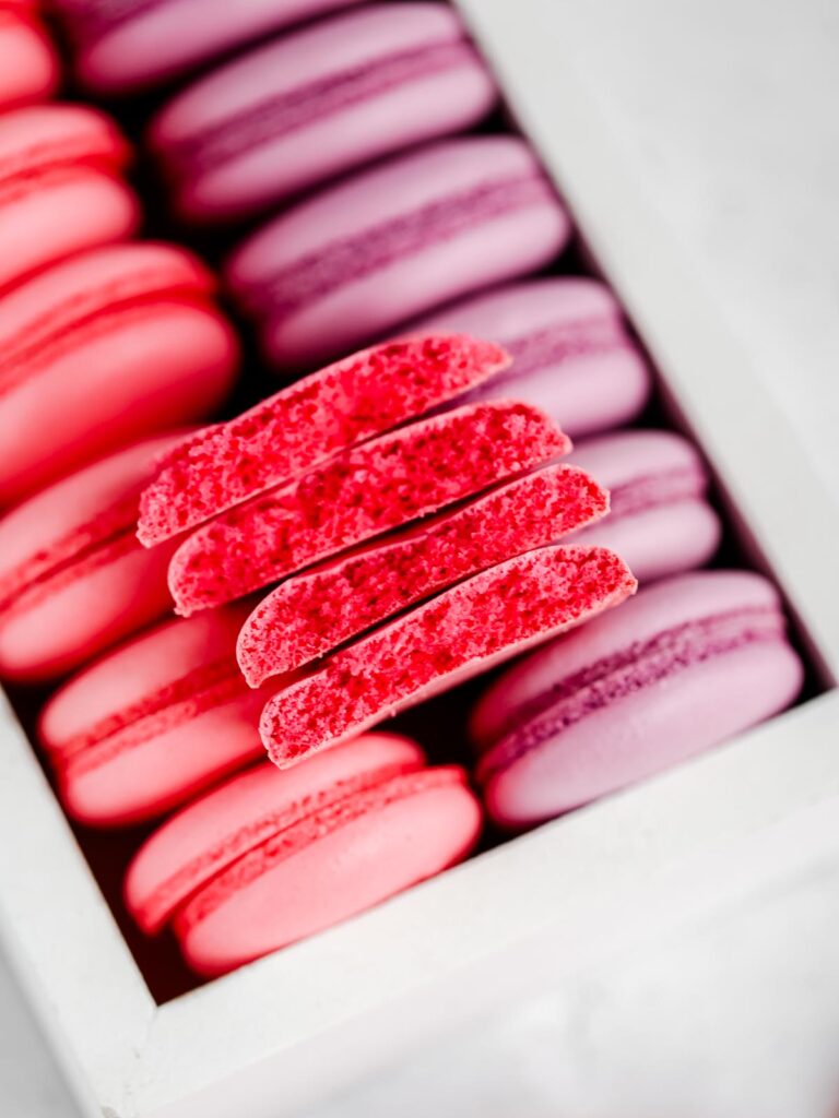 Pink and purple macaron shells in the box. 