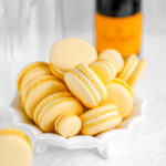Yellow macarons on the white plate and champagne on the background.