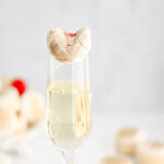 A glass of champagne with macarons on top.