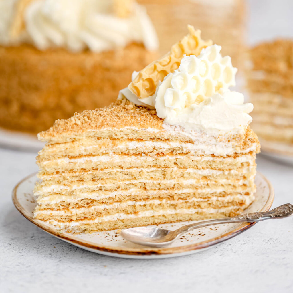 A piece of honey cake on the plate with a spoon.