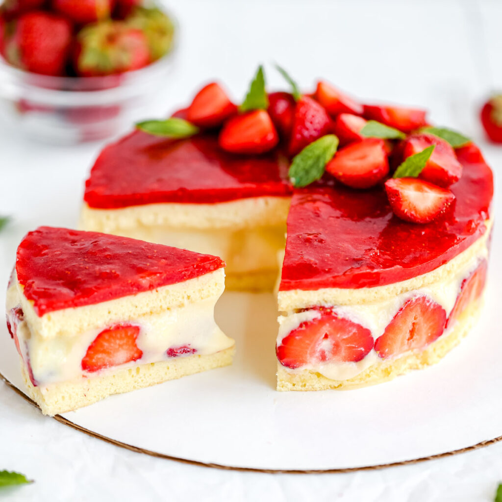 A cake decorated with fresh strawberries is on the table.