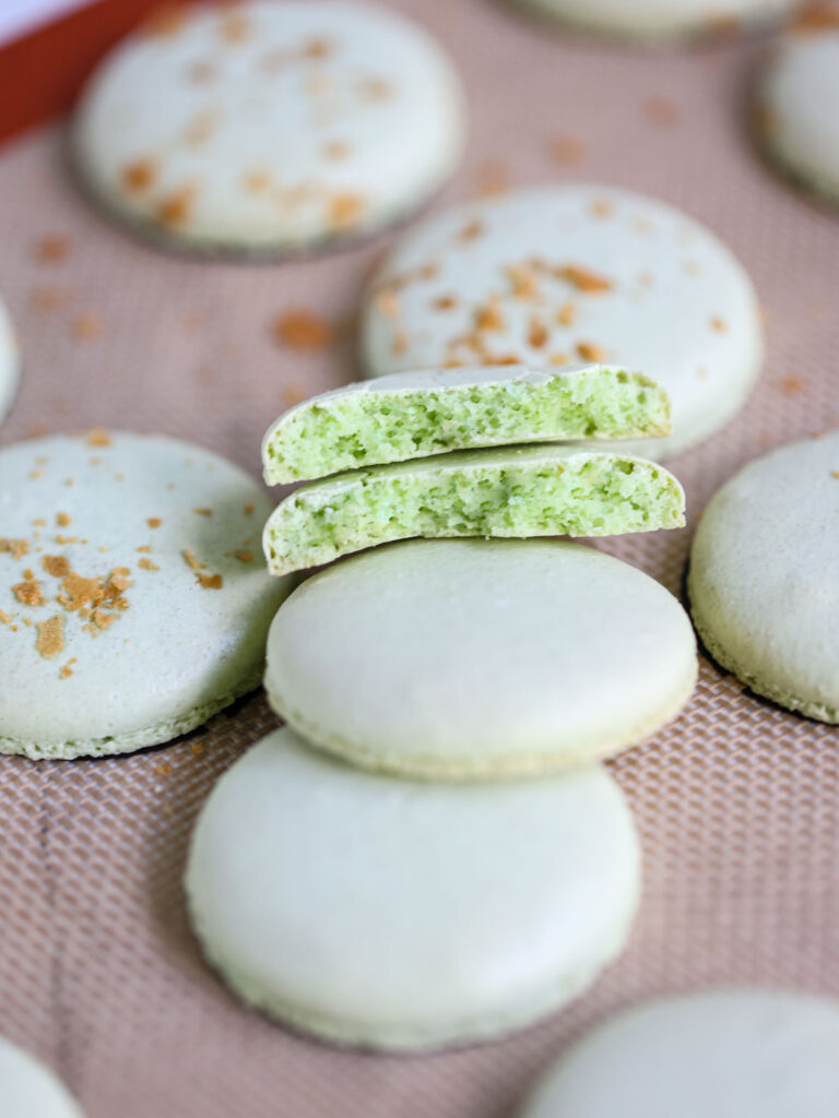 Macarons cut in half on the baking mat. 