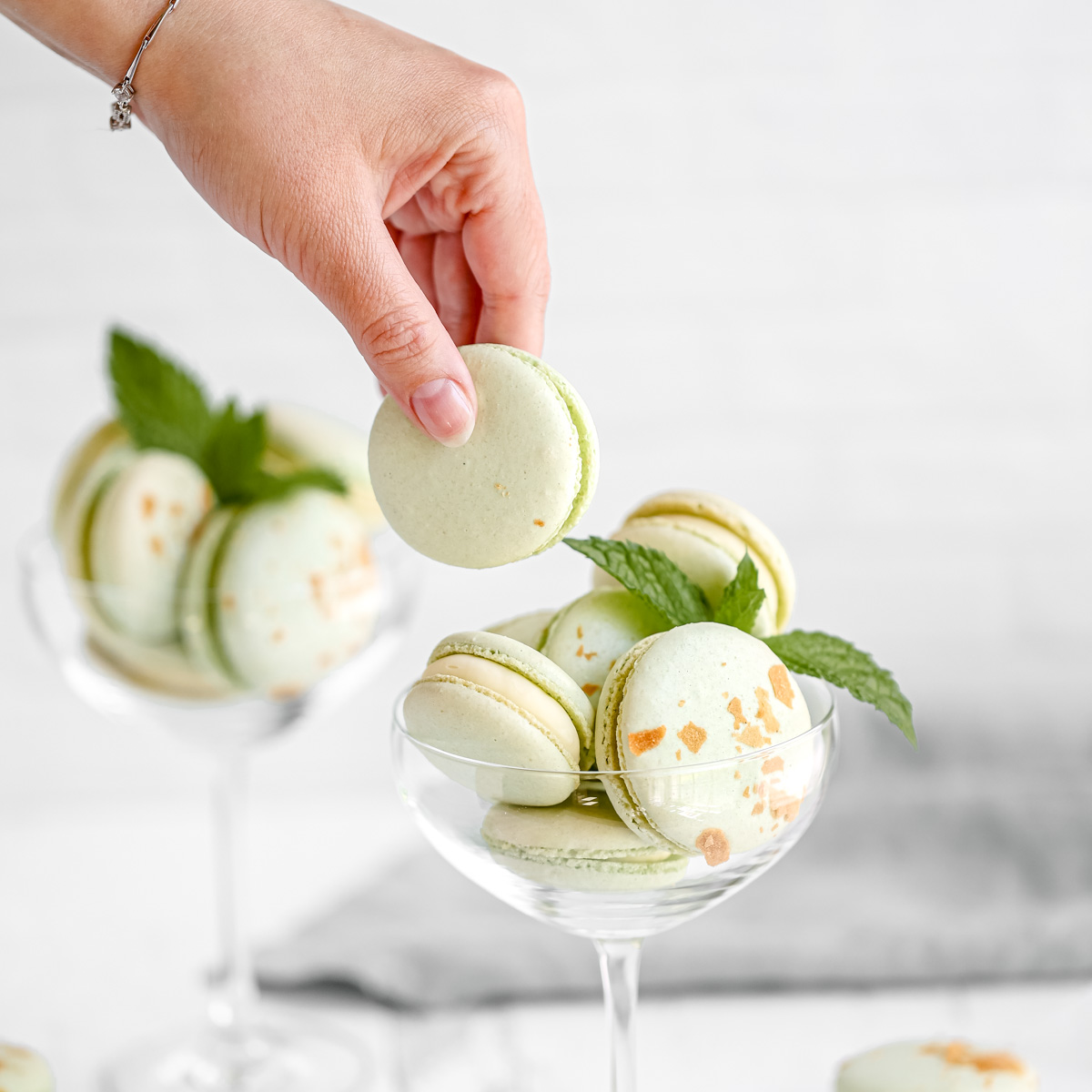 Green macarons in a martini glass with fresh mint.