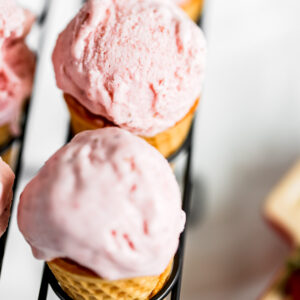 An ice cream cone with strawberry ice cream.