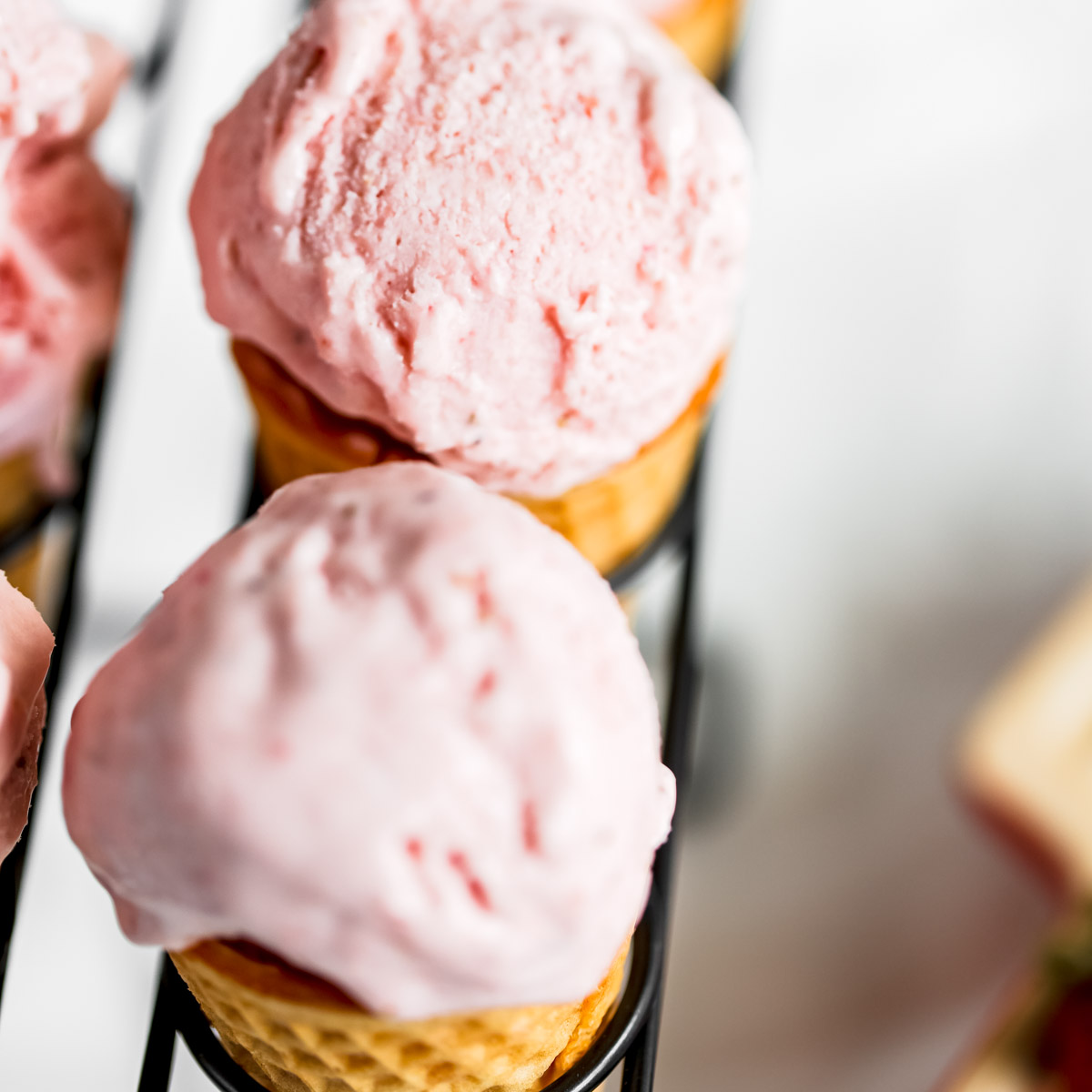 An ice cream cone with strawberry ice cream.