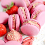 Dark pink macarons filled with strawberry cheesecake and crumbs.