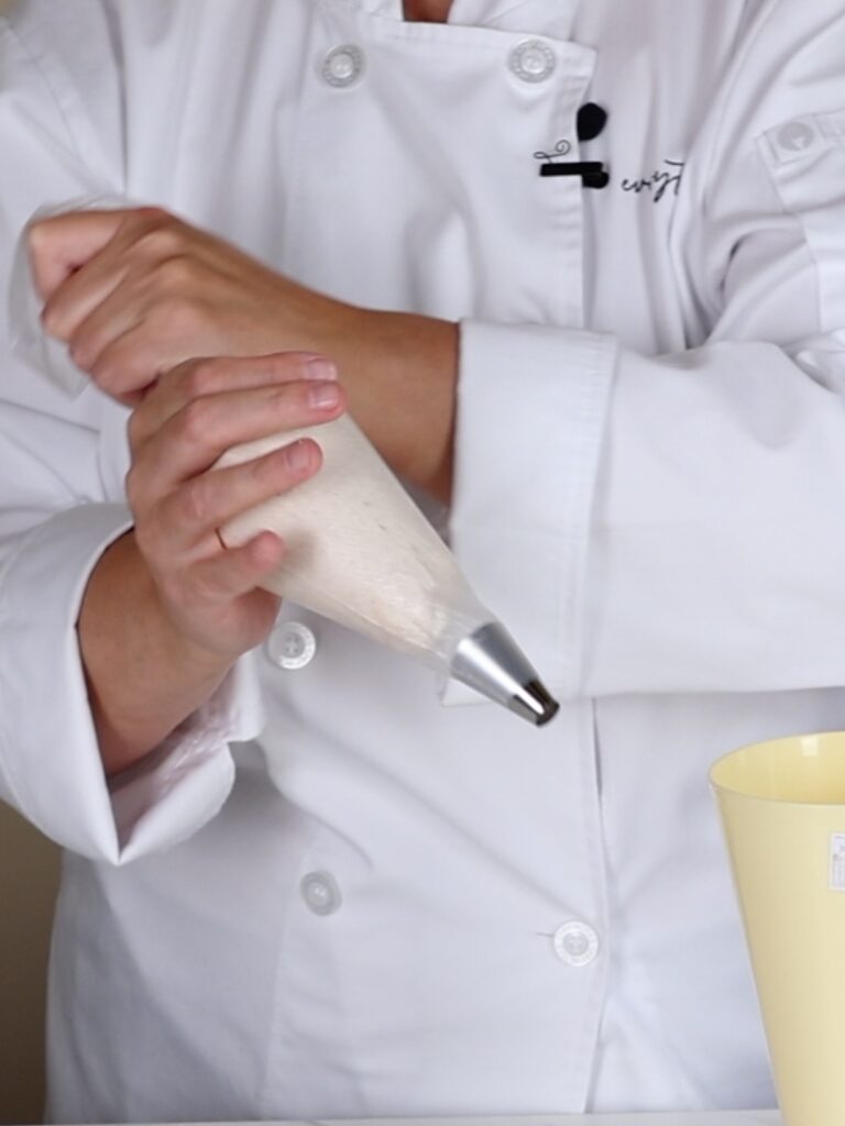 Hands are holding pumpkin spice buttercream in the pastry bag.