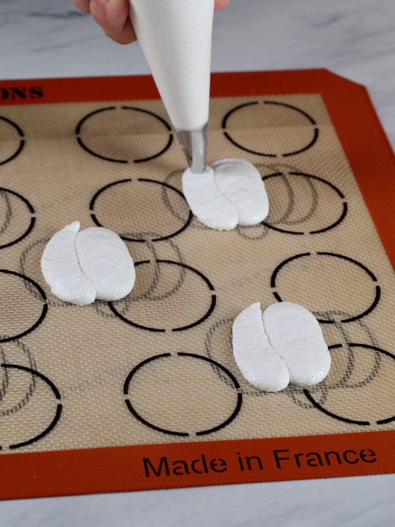 Piping the sides of pumpkin-shaped macarons.