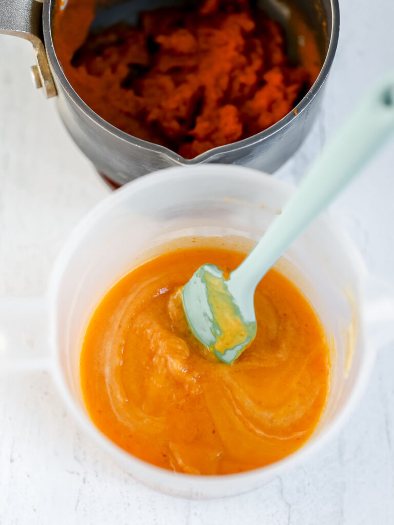 Melted white chocolate in the bowl with pumpkin puree. 