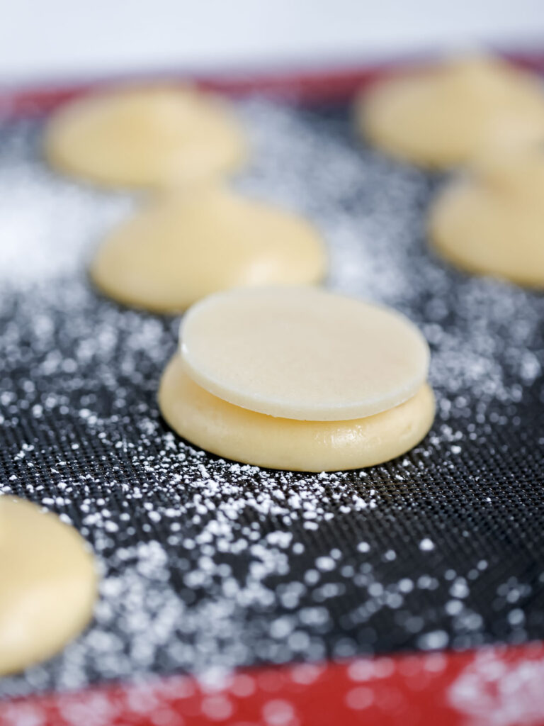 Piped round puffs on the baking mat. 