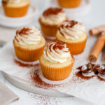 Cupcakes with frosting dusted with cocoa powder on the table with a spoon.