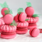 Pink macarons with mini macarons on top and green decor.