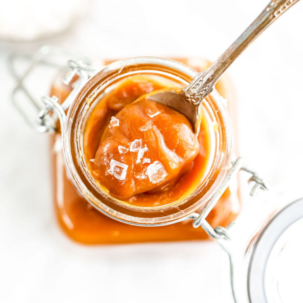 Homemade Salted Caramel in the glass jar with spoon.