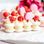 Macarons shaped as eclairs and decorated with fresh raspberries.