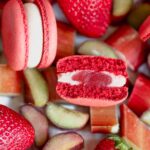 Red macaron cut in half with rhubarb and strawberries.
