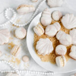 Macarons shaped like seashells on the plate with crumbs.