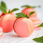 Peach macarons with fresh mint leaves.