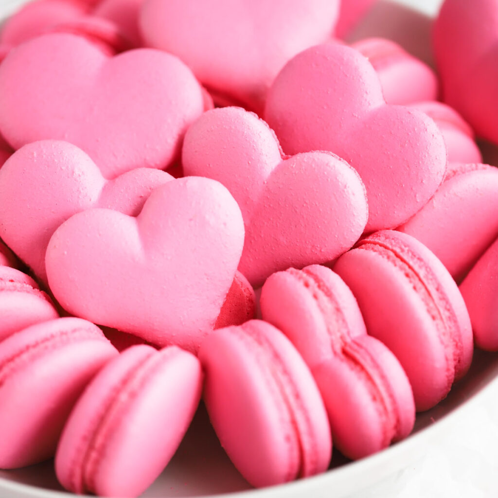 Heart-shaped macaron shells in the bowl.