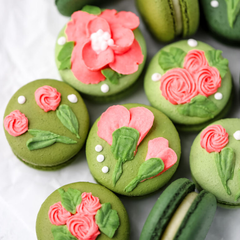 Green macarons decorated with pink flowers.