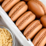 Brown macaron shells in the white box.