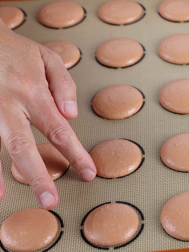 Finger touching the macaron shell. 