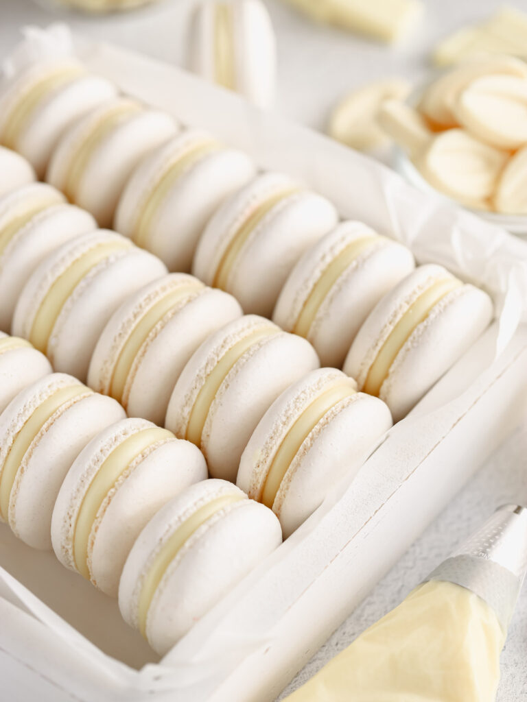 White macarons filled with white ganache are in the box. 