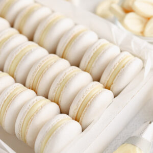 White macarons filled with white ganache are in the box.