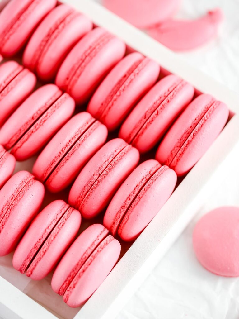 Pink macaron shells in the white box.