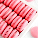 Pink macaron shells in the white box.