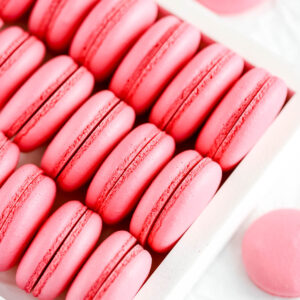 Pink macaron shells in the white box.