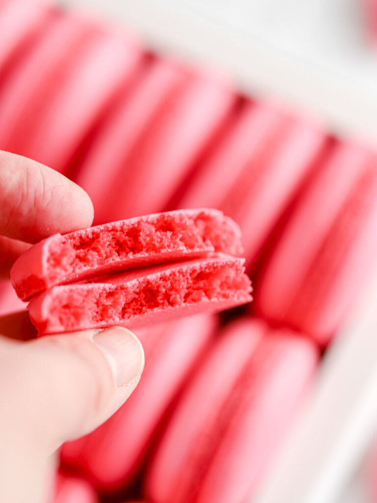Hand holding pink macaron shells.