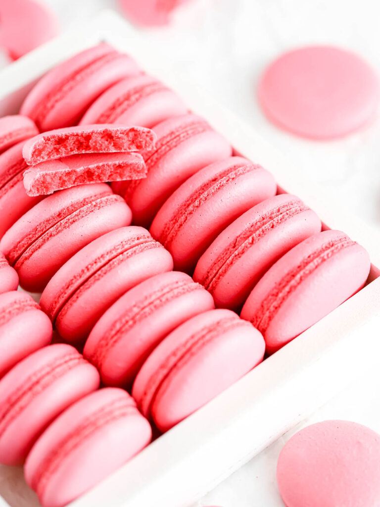 Pink macaron shells in the white box.