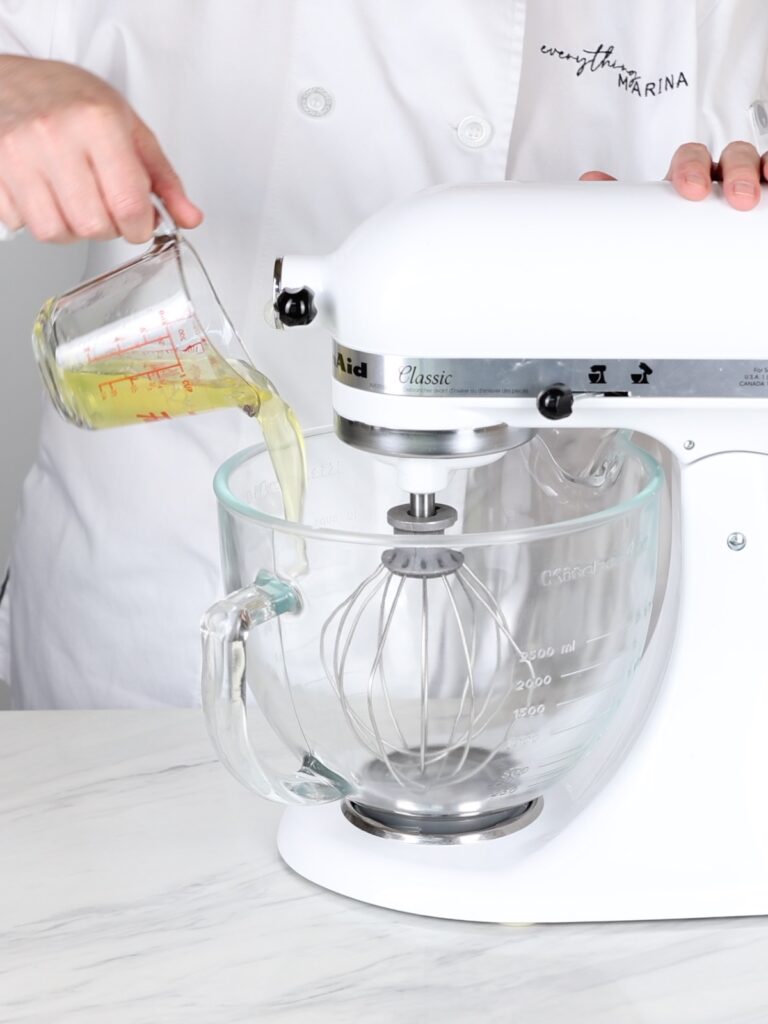 Pouring egg whites into the mixing bowl of the stand mixer.