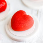 Red heart-shaped mousse cake covered with chocolate velour.