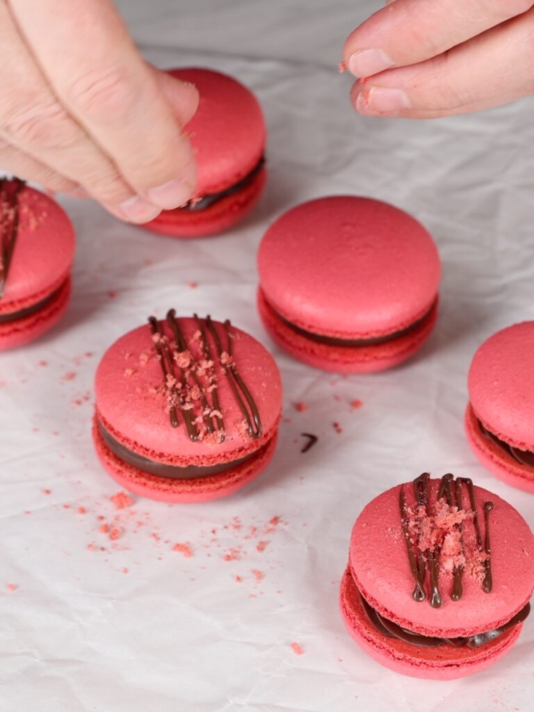 Decorating macarons with friezed dried strawberries. 