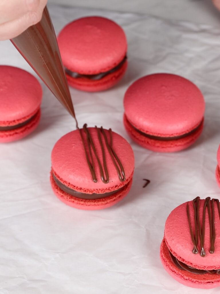 Decorating macarons with the chocolate. 