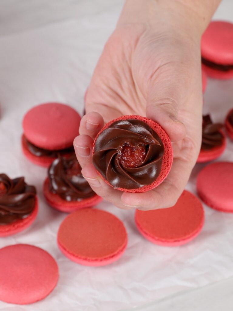 Chocolate ganache and strawberry confit on the macaron shell. 