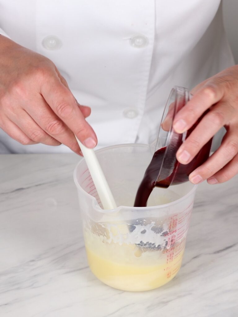 Adding blackberry puree to melted chocolate. 