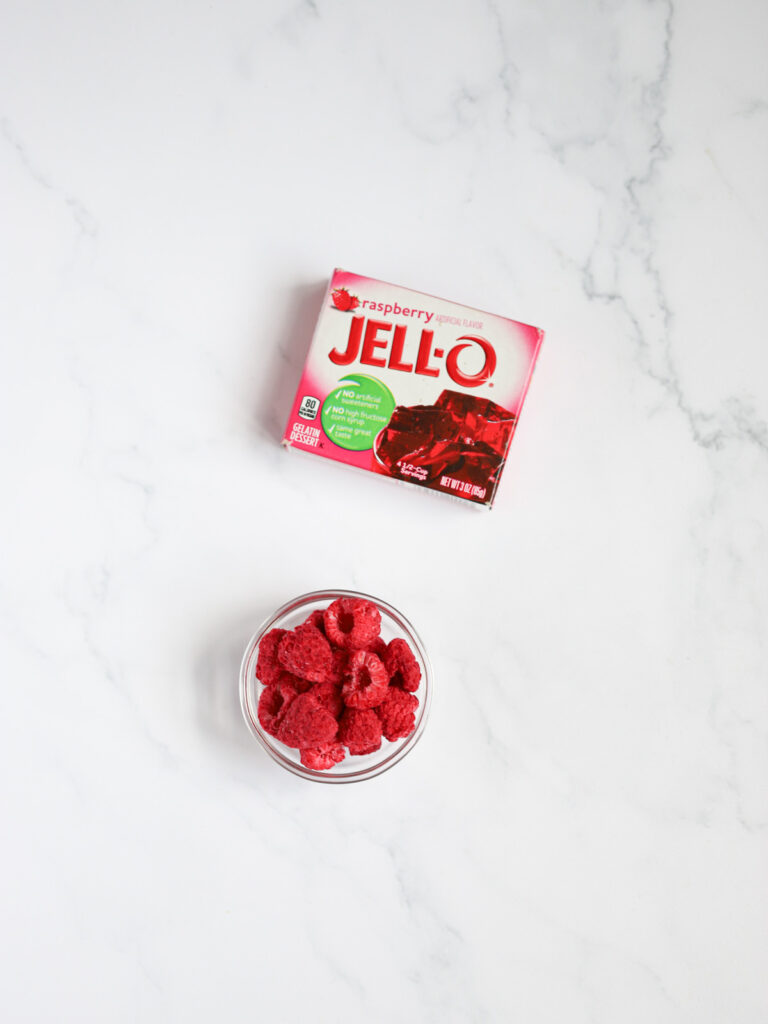 Raspberry jello and friezed dried raspberries are on the table. 
