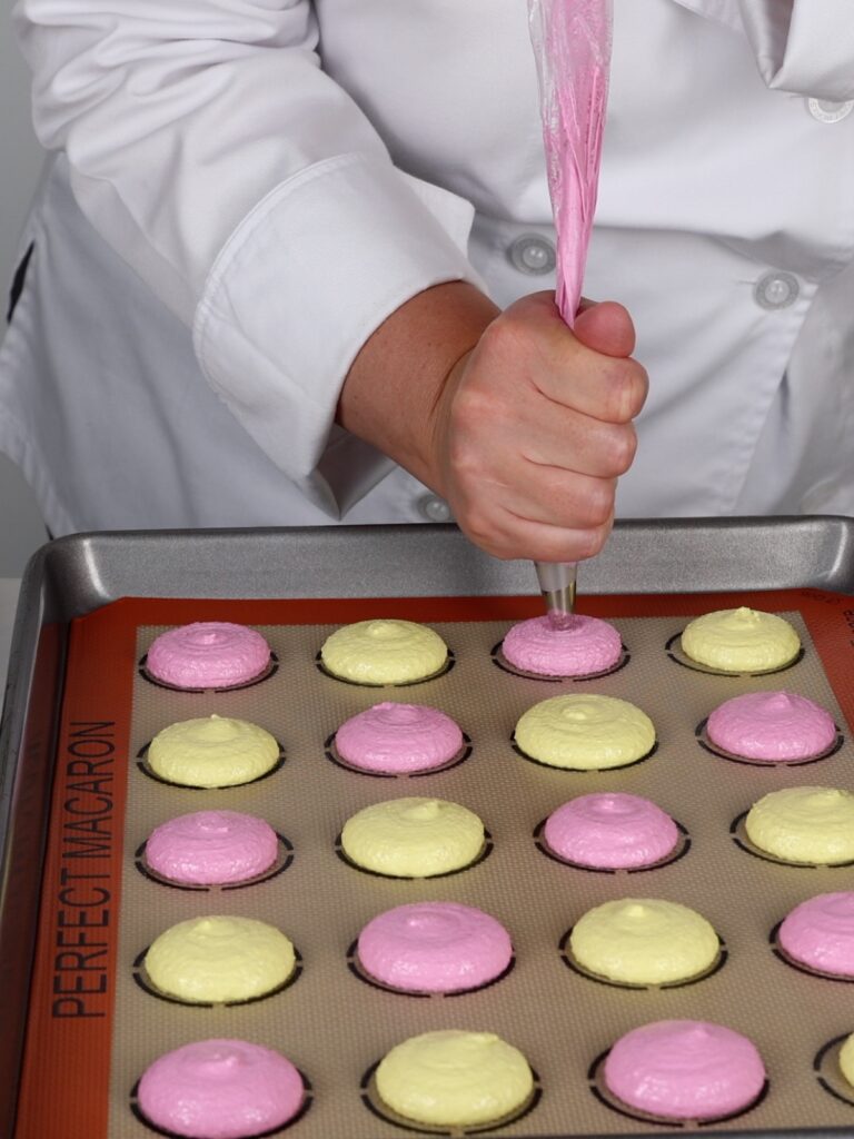 Piping macarons on the baking mat.