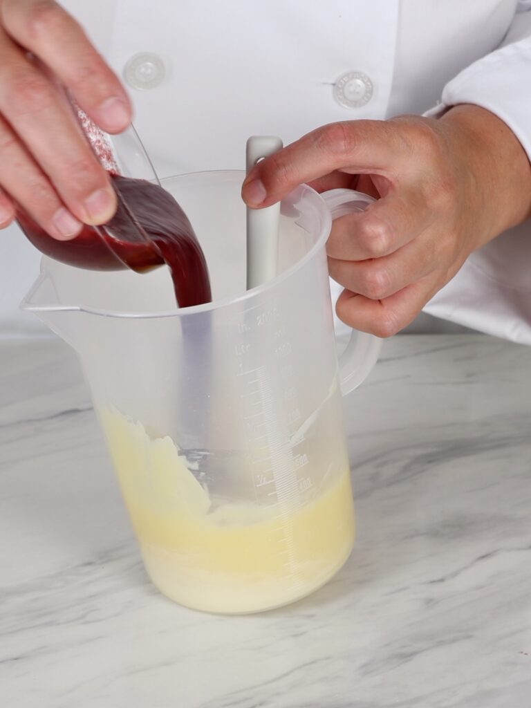 Pouring raspberry puree into melted chocolate. 